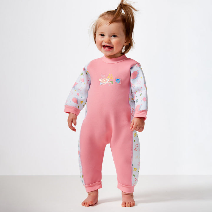 Little girl wearing a warm baby wetsuit in forest print with collar and cuffs 